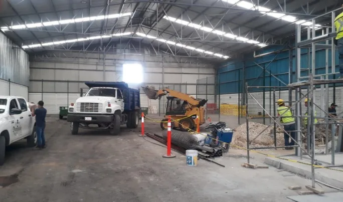 Interior de nave industrial con maniobras de carga y equipo en operación